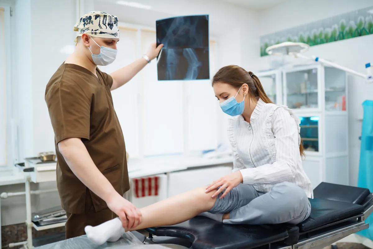 Médico avaliando exame de imagem do joelho de uma paciente